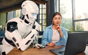 Robot and Human Sitting in front of a computer.
